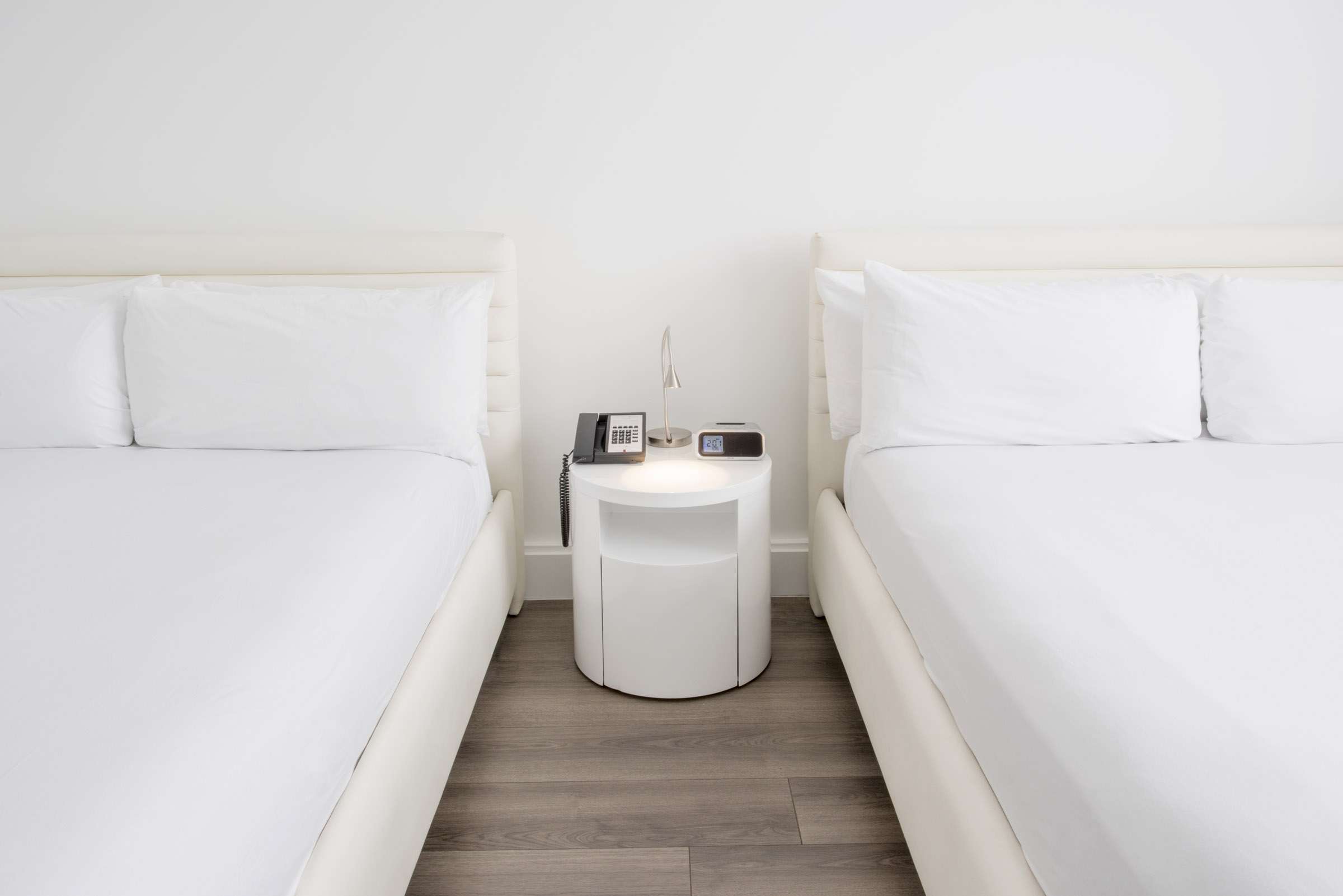 A hotel room with two twin beds and a round nightstand between them.