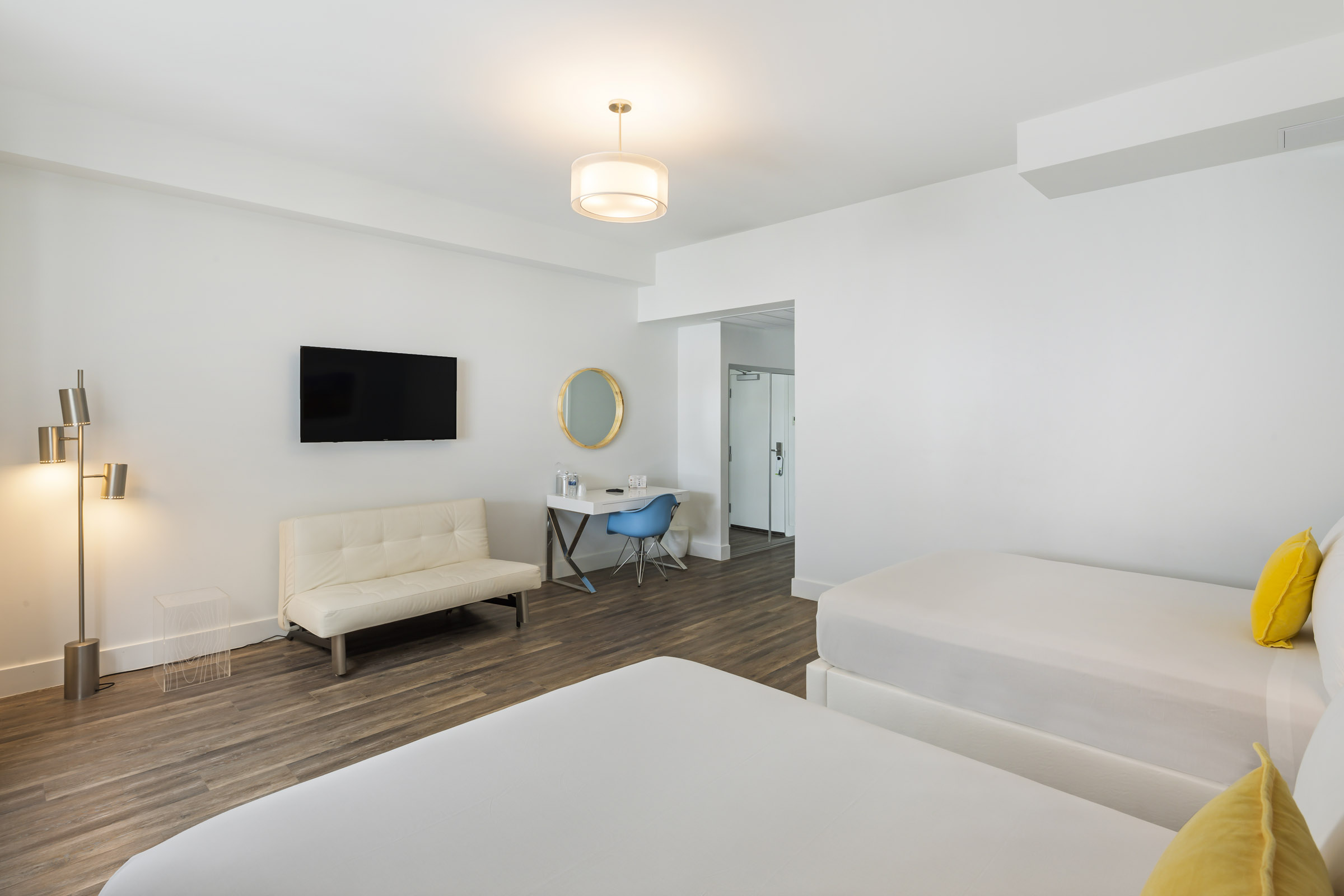 A modern hotel room with a large bed, sofa, desk, and TV.