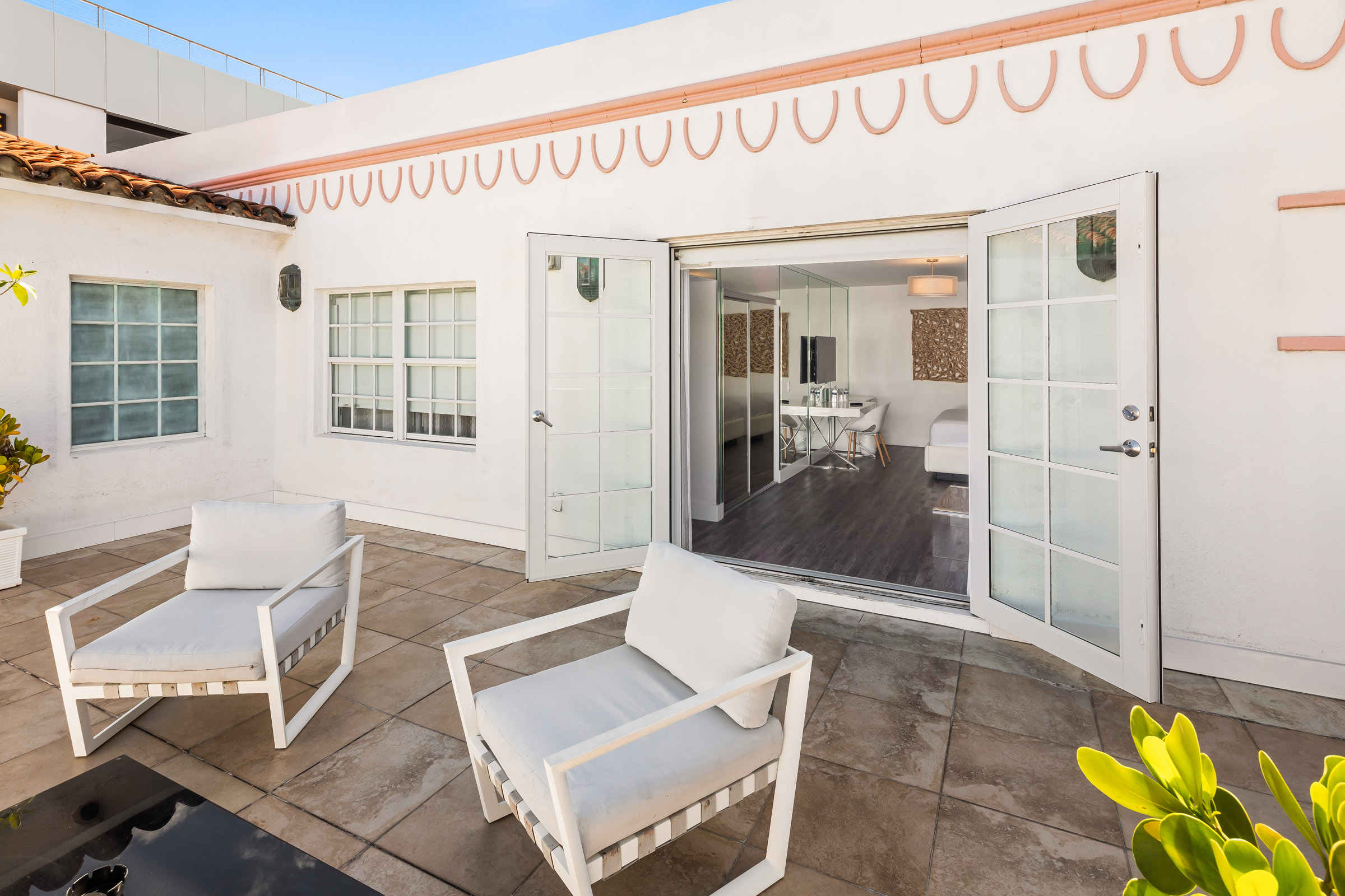 A white building with glass doors and outdoor seating area.